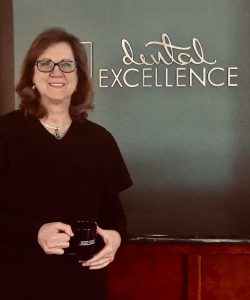 Woman posing in front of Dental Excellence sign