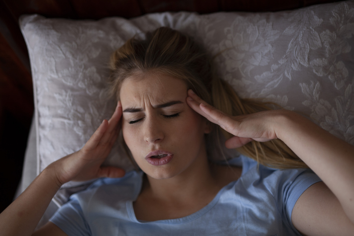 Woman experiencing migraine in bed