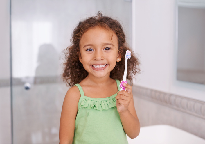Little girl smiling with pink toothbrush